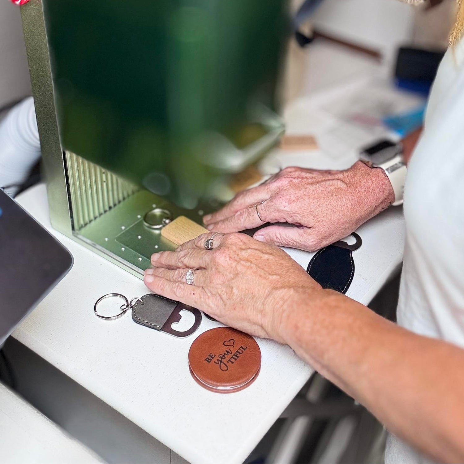 Close-up of live laser engraving in progress, engraving personalized leather keychains during an event.