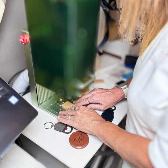 Close-up of live laser engraving in progress, engraving personalized leather keychains during an event.