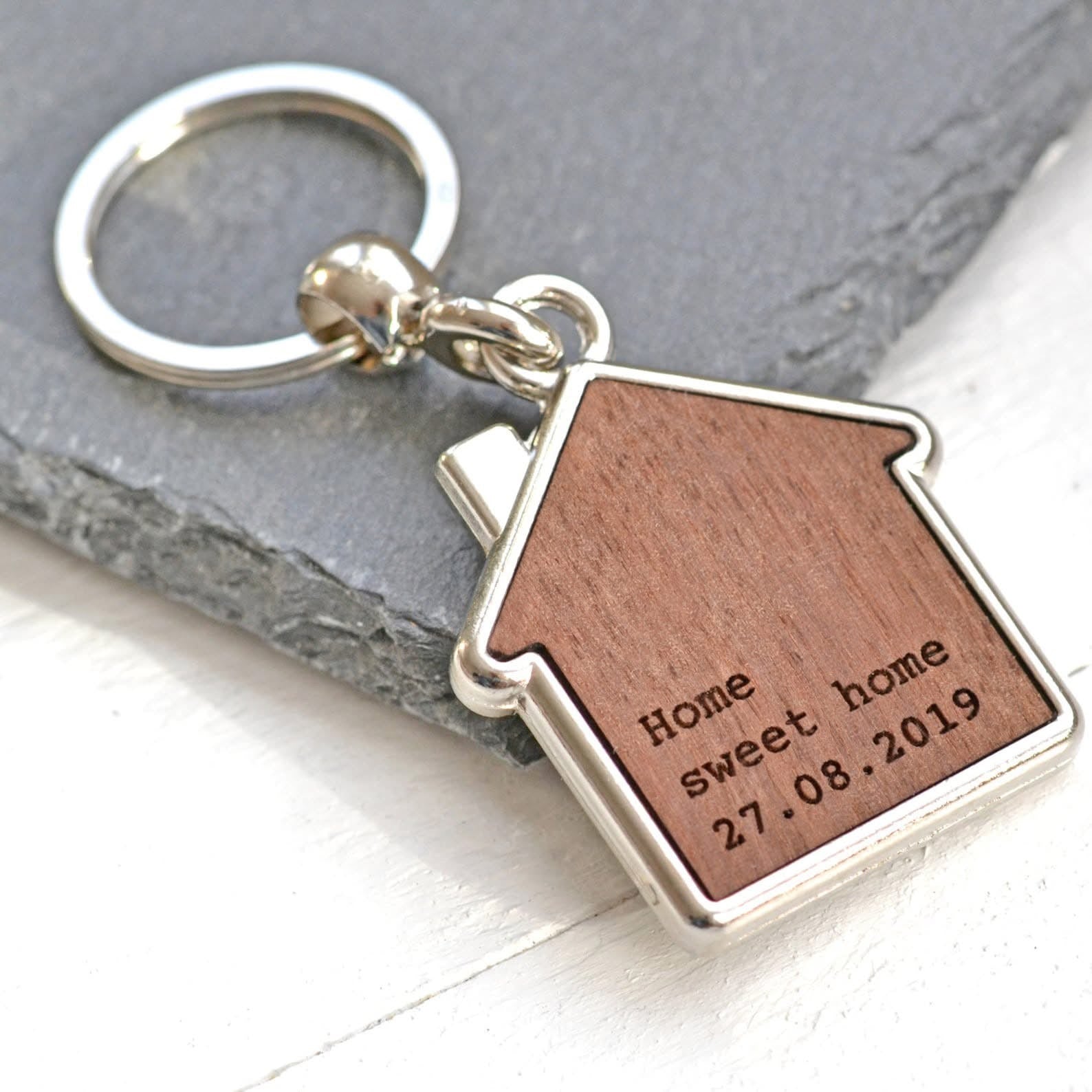 Keychain with wooden house-shaped tag and engraved text on a gray surface